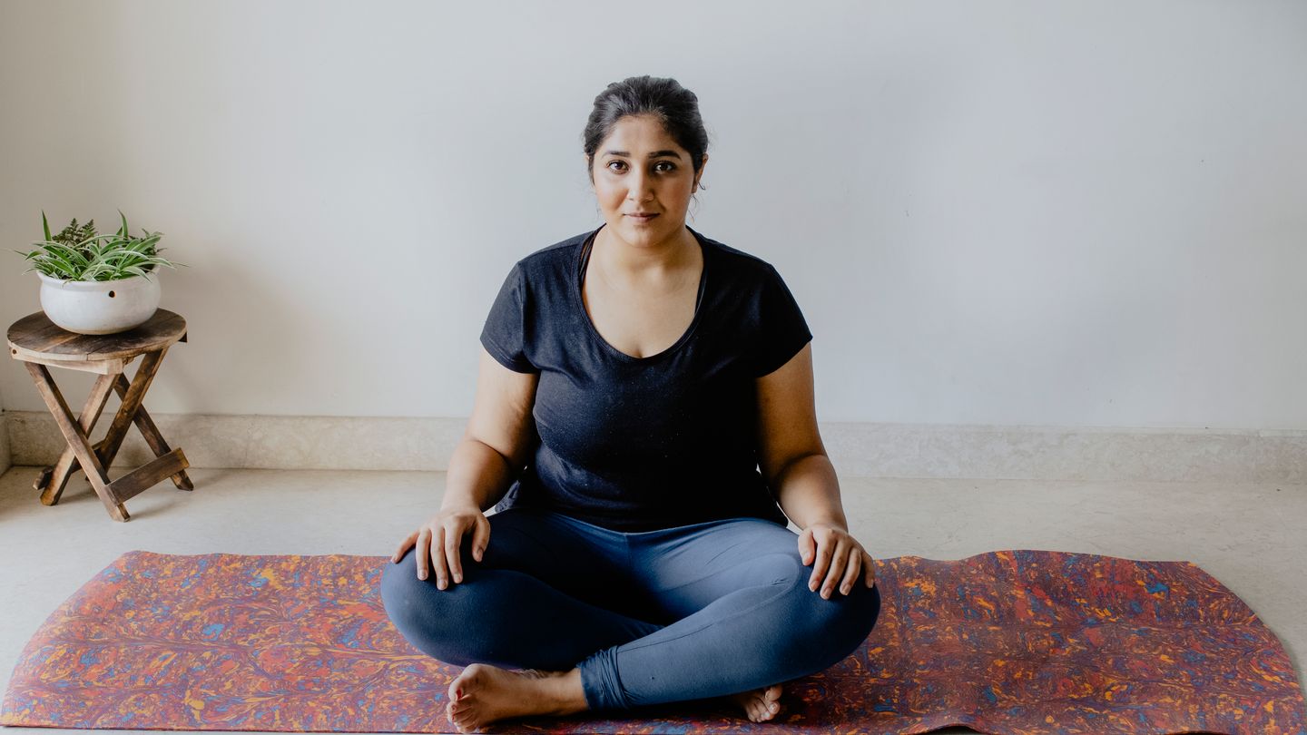 Woman in yoga pose meditating at home with copy space.